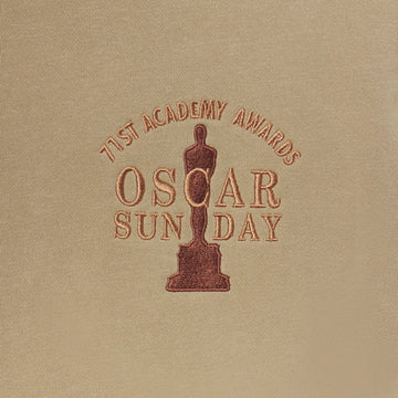 Embroidered Oscar statue and text on a beige fabric background